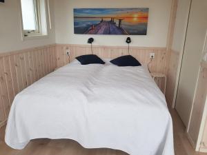 恩厄尔霍尔姆Storstugan & Lillstugan Kullabygden的卧室配有一张白色床,墙上挂着一幅画