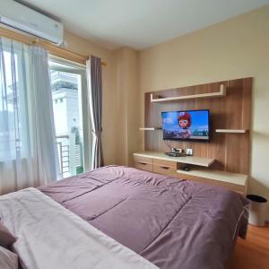 茂物Kozy Room Sentul Tower Apartemen的一间卧室配有一张床和一台平面电视