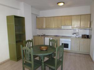 拉克鲁斯阿尔塔公寓式酒店的厨房配有绿色的桌椅和柜台。