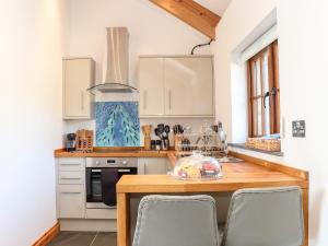 博德明Rosewarrick Cottage的厨房配有白色橱柜和木桌