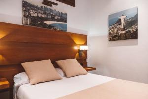 科尼尔-德拉弗龙特拉Ferreira Hostal Boutique的卧室配有白色的床和木制床头板