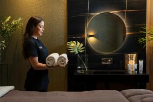梅利哈Lure Hotel & Spa - Adults Only的一名妇女站在酒店房间,拿着毛巾