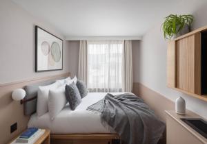 伦敦Inhabit Queen's Gardens, a Member of Design Hotels的卧室配有带枕头的床铺和窗户。