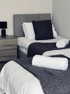 达尔基斯Dalkeith Five Bedroom House的一间卧室配有两张带白色床单的床和梳妆台。