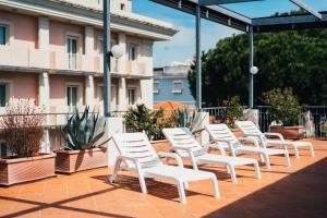 里米尼Arcangelo Roof Hotel的坐在庭院里的一排白色椅子