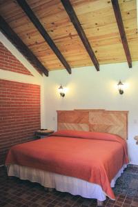 瓦斯卡坎波Cabañas Rincón Escondido的一间卧室设有红色的床和木制天花板