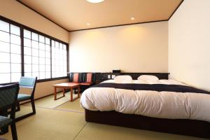 出云市麦斯雅日式旅馆的一间卧室配有一张床、一把椅子和窗户。