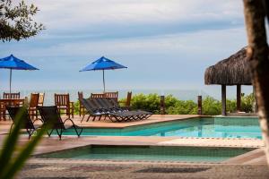 安谢塔Hotel Pontal de Ubu的一个带椅子和蓝伞的游泳池