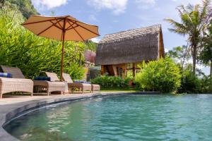 希德门Like living in a romantic Balinese painting的房屋旁的游泳池配有椅子和遮阳伞