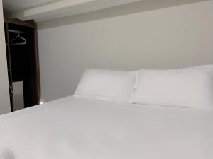 新加坡Hotel Calmo Chinatown的配有白色床单和枕头的宿舍间内的一张床位