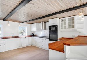 霍伊斯莱乌Lundø的厨房配有白色橱柜和木制天花板
