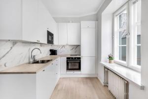 赫尔辛基WeHost Modern Scandinavian Studio in Trendy Kallio的白色的厨房配有白色橱柜和水槽