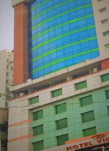 达卡Hotel Victory - Best in City Center的一座高大的建筑,设有绿色和蓝色的窗户