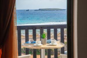 Diakofti波尔图迪亚柯福蒂酒店的俯瞰大海的阳台的桌子,上面有杯子和碟子