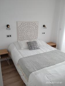 卢戈Apartamento Isaac junto a la muralla Romana的卧室配有一张带两张桌子的大型白色床