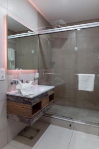 马普托Polana Plaza Hotel的一间带玻璃淋浴和水槽的浴室