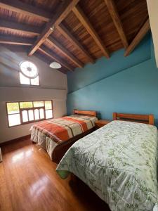 CarhuazLodge Acopampa Inn的配有两张床铺的蓝色墙壁和窗户