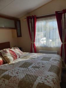 滨海圣佩La Chanterie Agréable Mobil-Home Résidentiel Normand的一间卧室配有一张带红色窗帘的床和一扇窗户