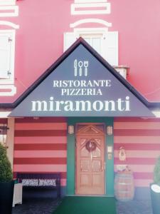 布伦托尼科Miramonti B&B cucina&pizza的粉红色的建筑,上面有标志,上面写着快乐的历史普拉明尼苏达