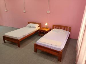MacangHomestay Machang Sentral的配有粉红色墙壁的客房内的两张床