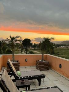 弗洛里亚诺波利斯Pousada Ilha dos Anjos的阳台享有日落美景,设有长凳和棕榈树