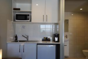 KallangurKallangur Motel的厨房配有白色橱柜、水槽和微波炉