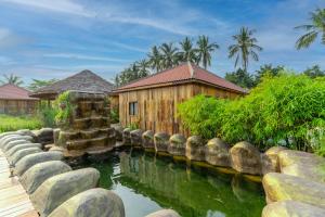 暹粒Authentic Khmer Village Resort的楼前有池塘的房子