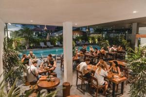暹粒暹粒恩内德兹旅舍的一群人坐在带游泳池的餐厅的桌子上