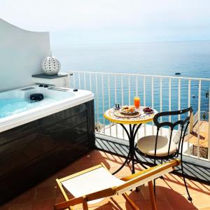 波西塔诺Villa Fortuna的阳台设有热水浴池和桌椅。