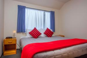 基督城布什院长旅馆的一间卧室配有一张带红色枕头的大床