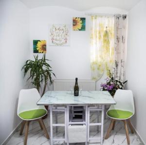 锡比乌Wall St House的一间设有白色桌子和两把绿色椅子的用餐室