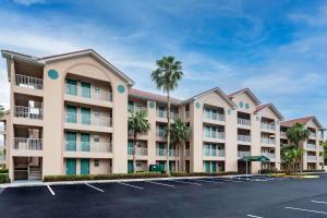 基西米Vacation Villas 2, a Ramada by Wyndham的停车场内棕榈树的大型公寓楼
