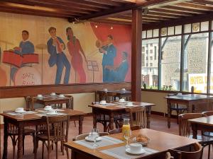滨海圣奥班诺曼底酒店的餐厅设有木桌,墙上挂有绘画作品