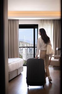 费特希耶La Farine Hotel的一位妇女站在酒店房间,带着手提箱