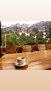 TropojëGuest House Emanueli的一边在木桌边一边欣赏美景一边享用咖啡