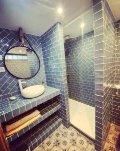 马赛Vaste loft plein de charme au cœur de Marseille的蓝色瓷砖浴室设有水槽和镜子