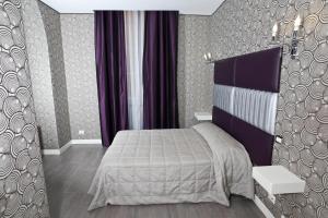 罗马那蒂兹美洲酒店的一间卧室配有一张床和紫色窗帘