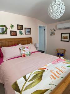 皮克图Seabank House Bed and Breakfast Aloha的一间卧室配有一张带粉色床单和吊灯的床。