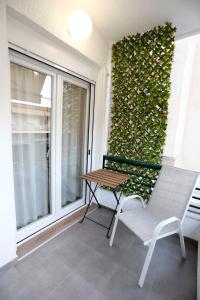 尼亚·蒙达尼亚Bianca Suites的阳台配有一张椅子和一张桌子,阳台设有常春藤墙