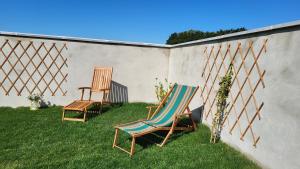 DallonGîte de la Roulotte de l'Epine的两把椅子坐在墙上的草上
