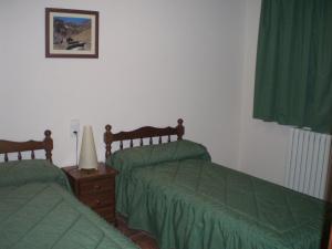 Pal博内特公寓的一间卧室配有两张带绿盖的床和一盏灯