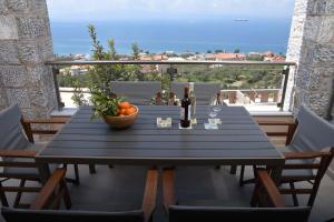 卡拉马塔Villa Dafni的阳台上摆放着一碗橘子和酒杯的桌子