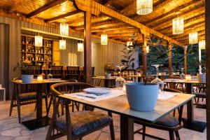 梅加利阿莫斯Skiathos Avaton Suites & Villas, Philian Hotels and Resorts的餐厅设有木桌和椅子及灯