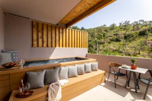 梅加利阿莫斯Skiathos Avaton Suites & Villas, Philian Hotels and Resorts的阳台享有带热水浴池的房屋景致。