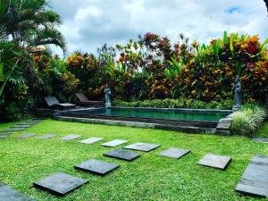 乌布Pondok Naya - CHSE Certified的花园内的一个游泳池,花园内种有草地和树木