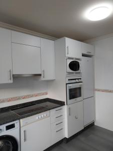 卢戈Apartamento Calzada Romana的白色的厨房配有白色橱柜和电器