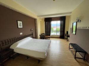 蓬特德乌梅Hotel Eumesa的一间卧室配有一张床、一张桌子和一个窗户。