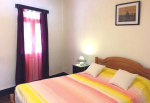 圣维森特Holidays Madeira的一间卧室配有一张带彩色毯子和窗户的床。