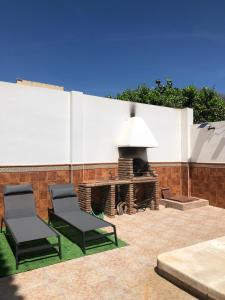 马拉加Apartamento con piscina en Ciudad Jardín的庭院设有两把椅子和壁炉