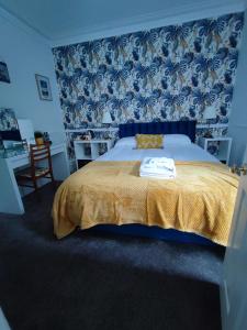 伊尔弗勒科姆斯高谷乡间别墅旅馆的一间卧室配有一张黄色毯子和蓝色壁纸的床